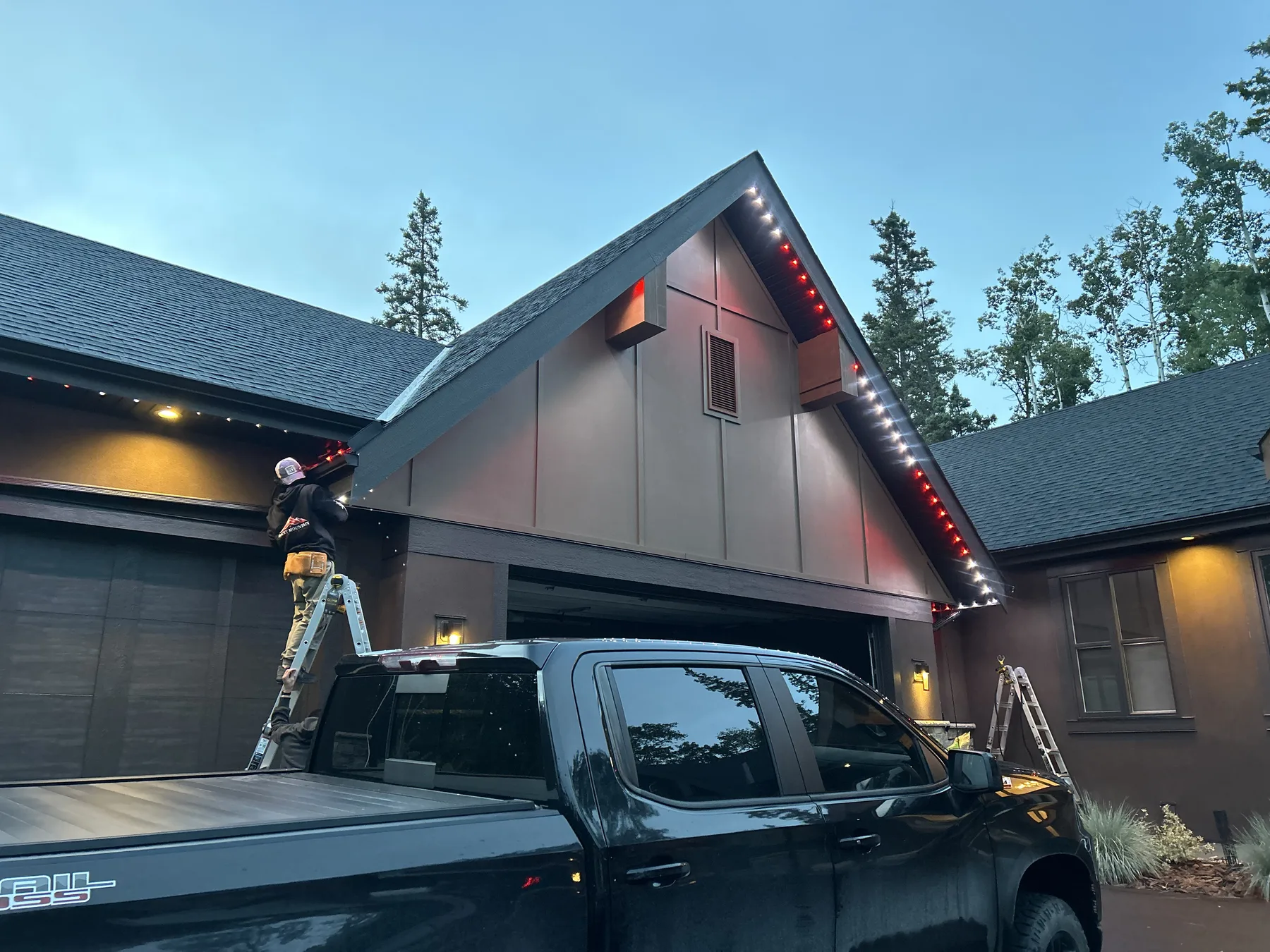 Rocky Mountain Lighting installer working on a home's illuminated roofline