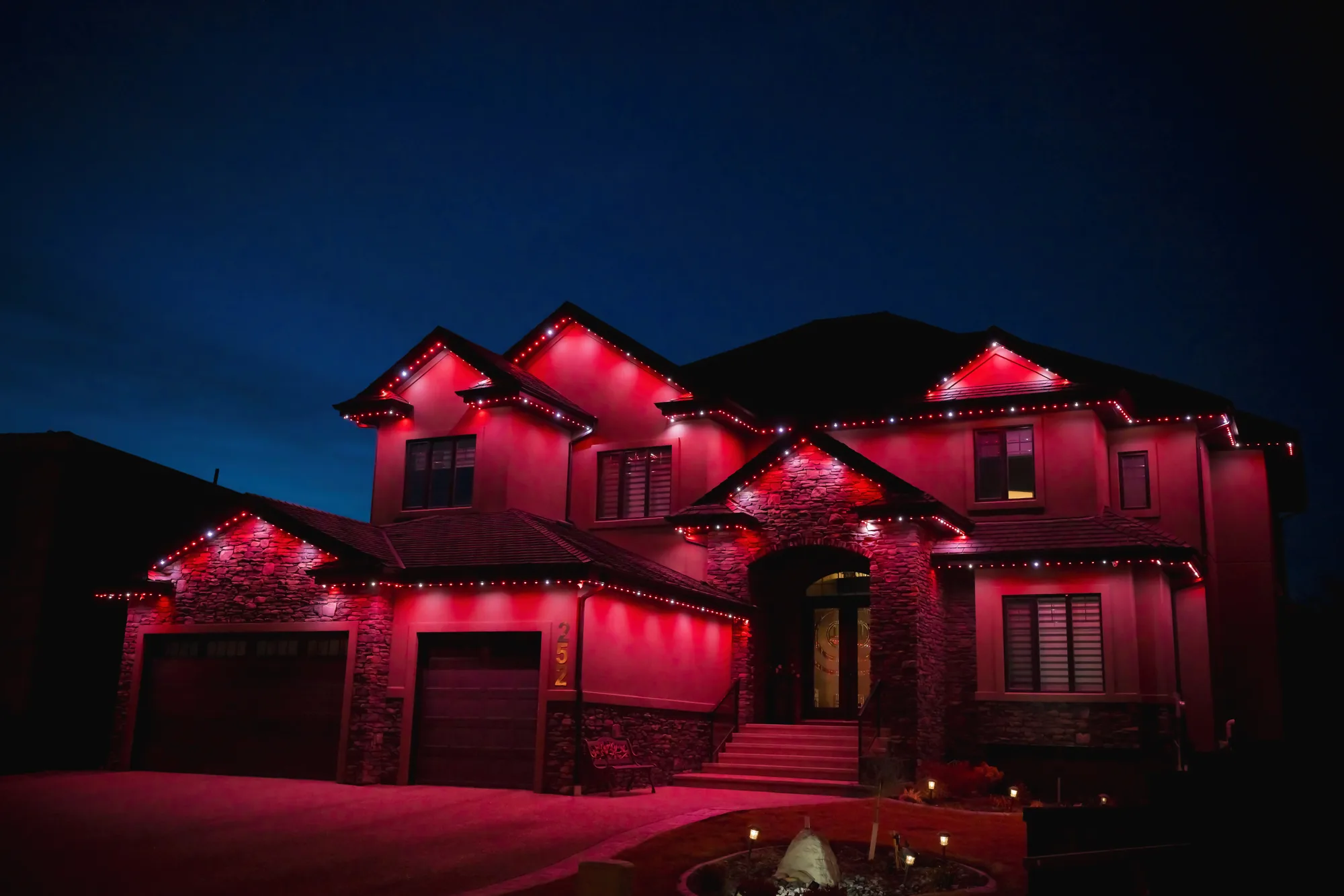Home illuminated with red permanent roofline lighting