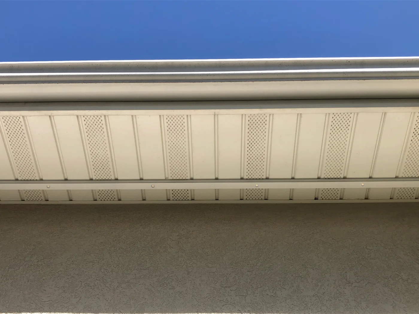 Professionally installed permanent-lighting track aligned beneath a white roof soffit