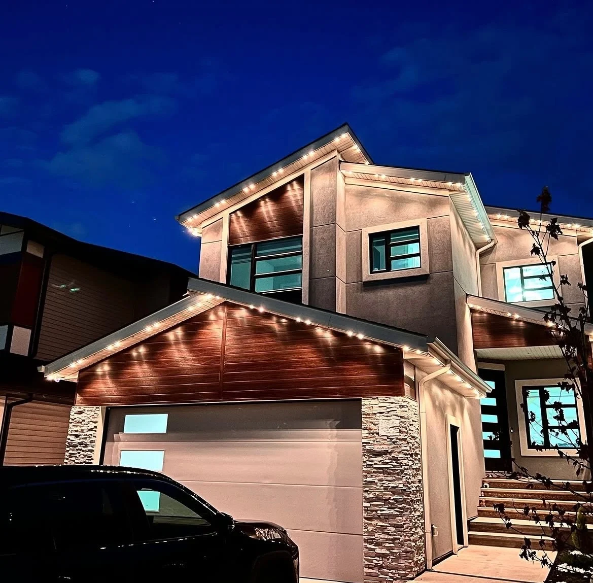 Modern home displaying warm-white Canstar permanent roofline lighting at night