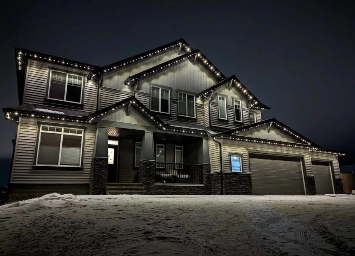 Large Edmonton-area home with warm-white permanent roofline lighting on a snowy winter night